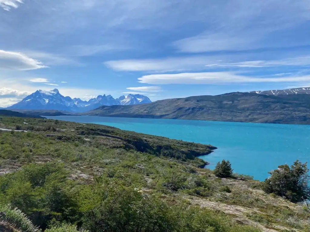 Bright turquoise lake with snow-capped mountains rising behind it in Torres del Paine National Park. If you love hiking, it's worth considering adding a stop in Torres del Paine, Chile to your Argentina itinerary.
