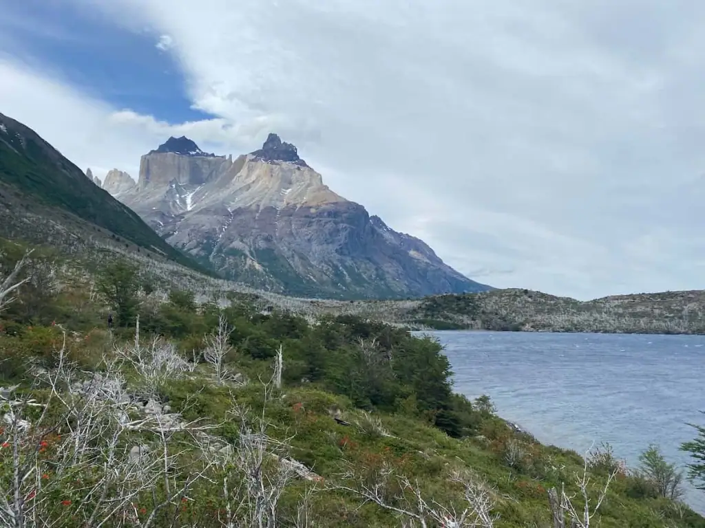 View of Cuernos del Paine, the dramatic horn-shaped peaks of Torres del Paine National Park, framed by a cloudy sky and lake while on the French Valley hike.
