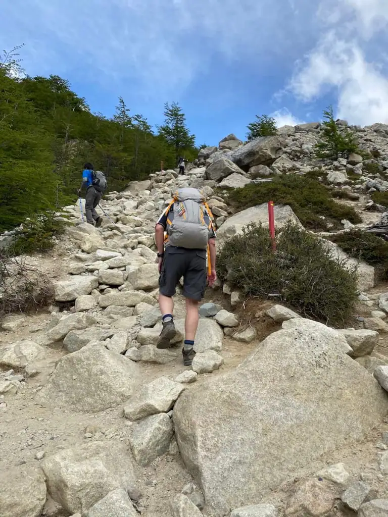 Hikers climbing a steep, rocky trail towards the end of the Mirador las Torres hike in Torres del Paine.