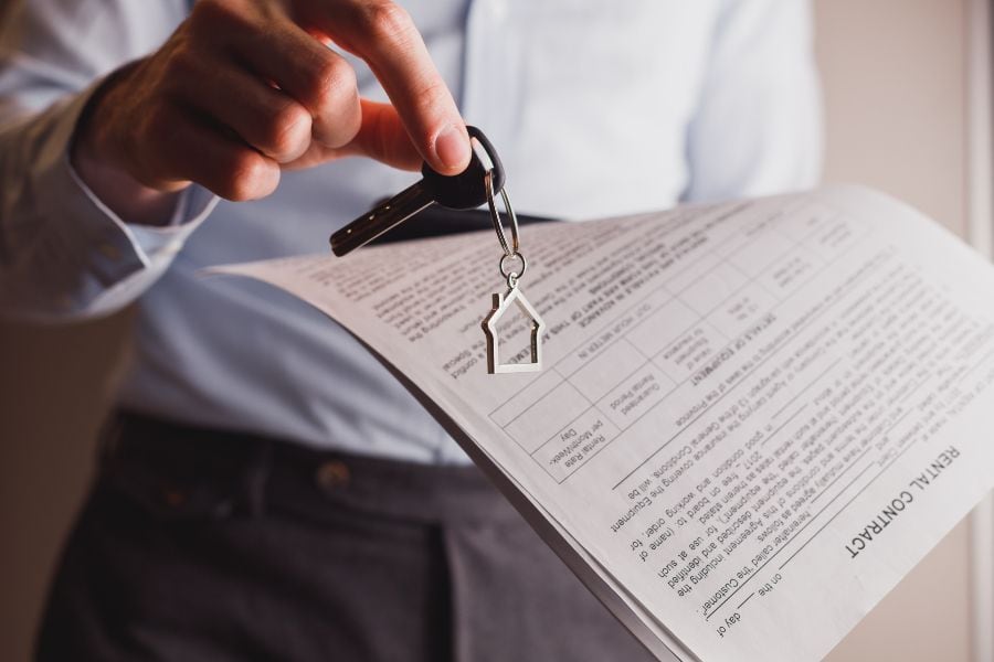 Person holding rental contract and house keys, highlighting essential documents for private rentals.