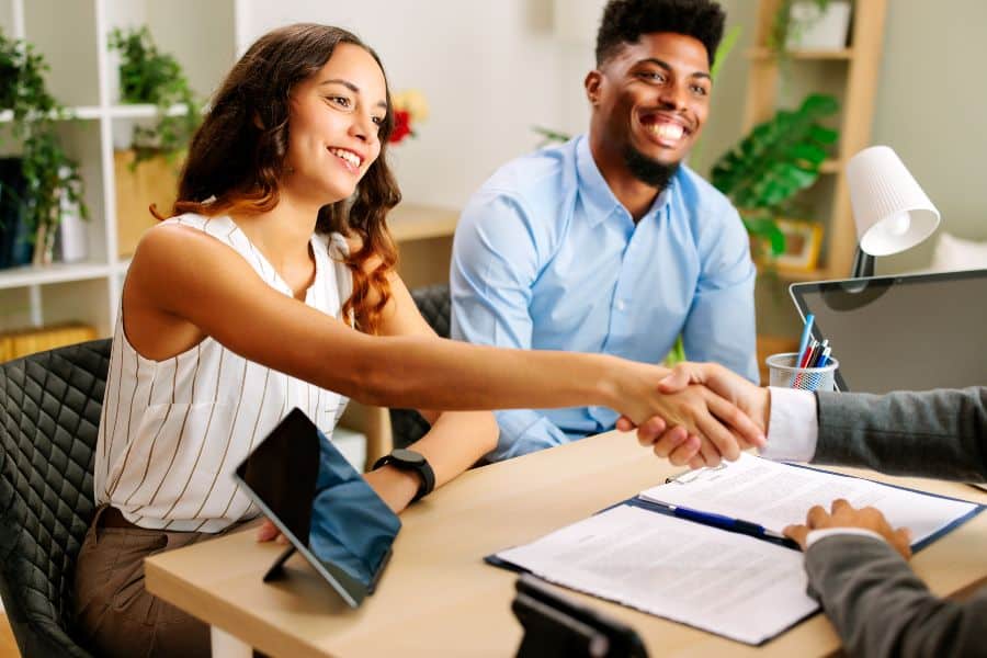 Couple shaking hands with an agent during a rental meeting, symbolising smart private rental decisions.