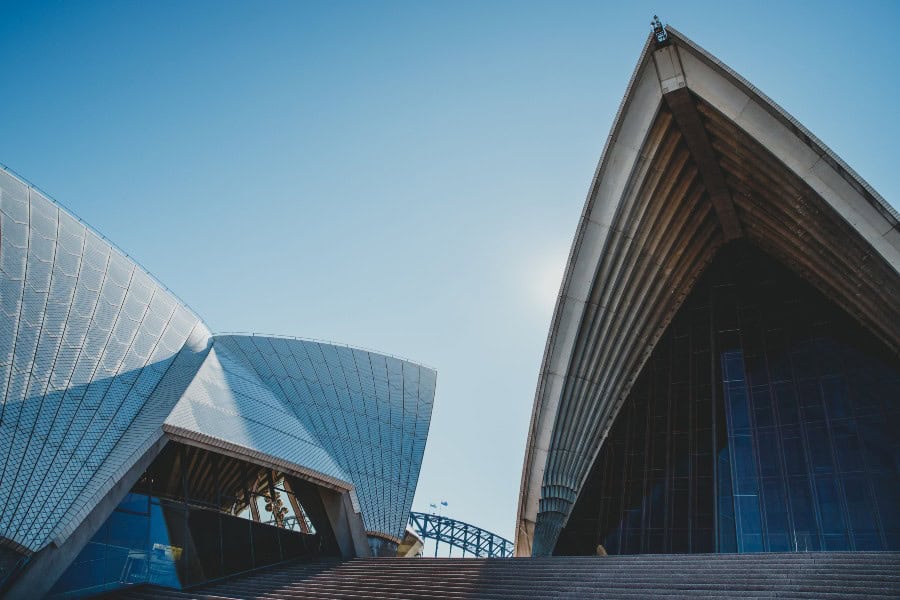 Low-angle view of the Sydney Opera House sails against a clear blue sky on a sunny day.