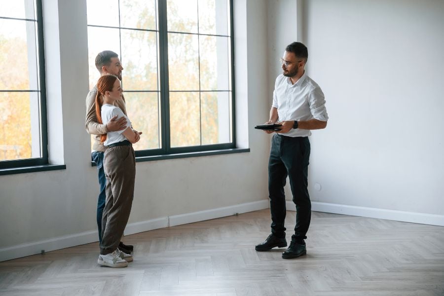 Couple viewing an empty apartment with a real estate agent after a rental setback.