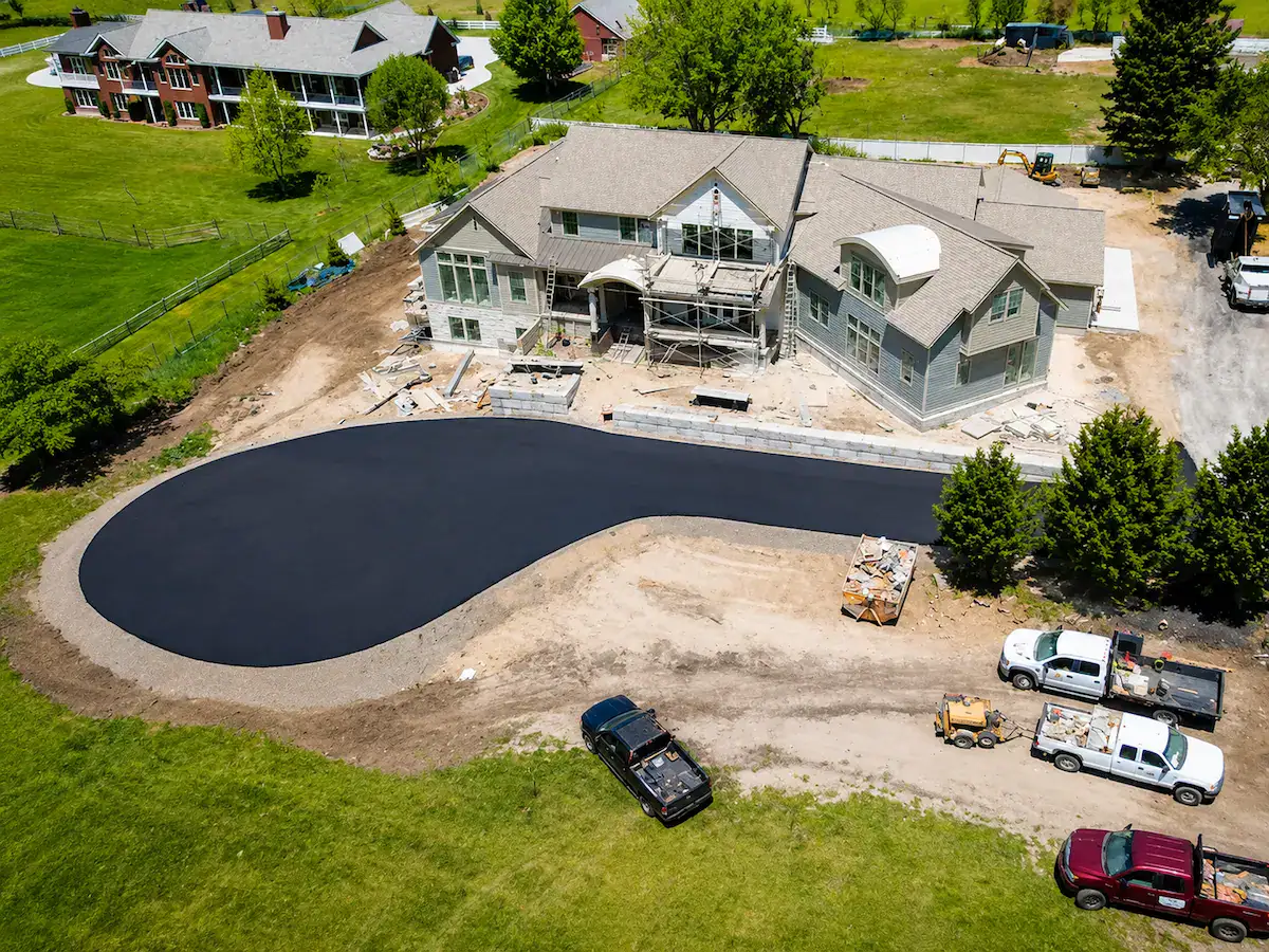 Aerial view of new residential asphalt driveway installation at luxury Utah home