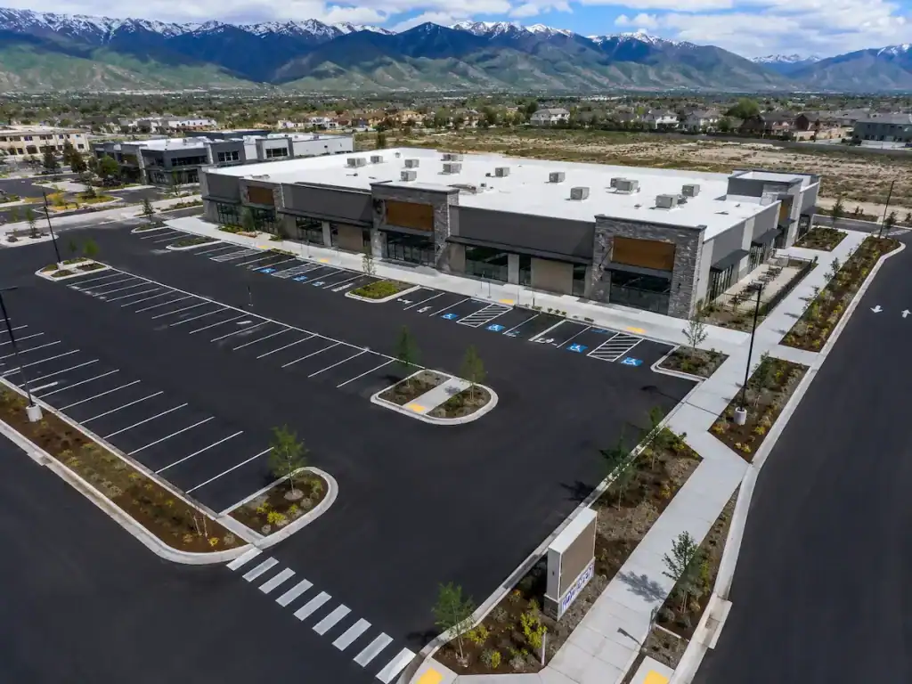 Commercial property in Utah featuring concrete sidewalks, curbs, ADA ramps, landscaped islands, and fresh asphalt paving.