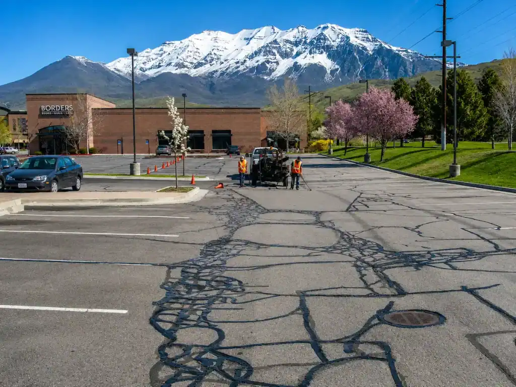 Commercial parking lot crack sealing project in Utah with snow-capped mountains in the background
