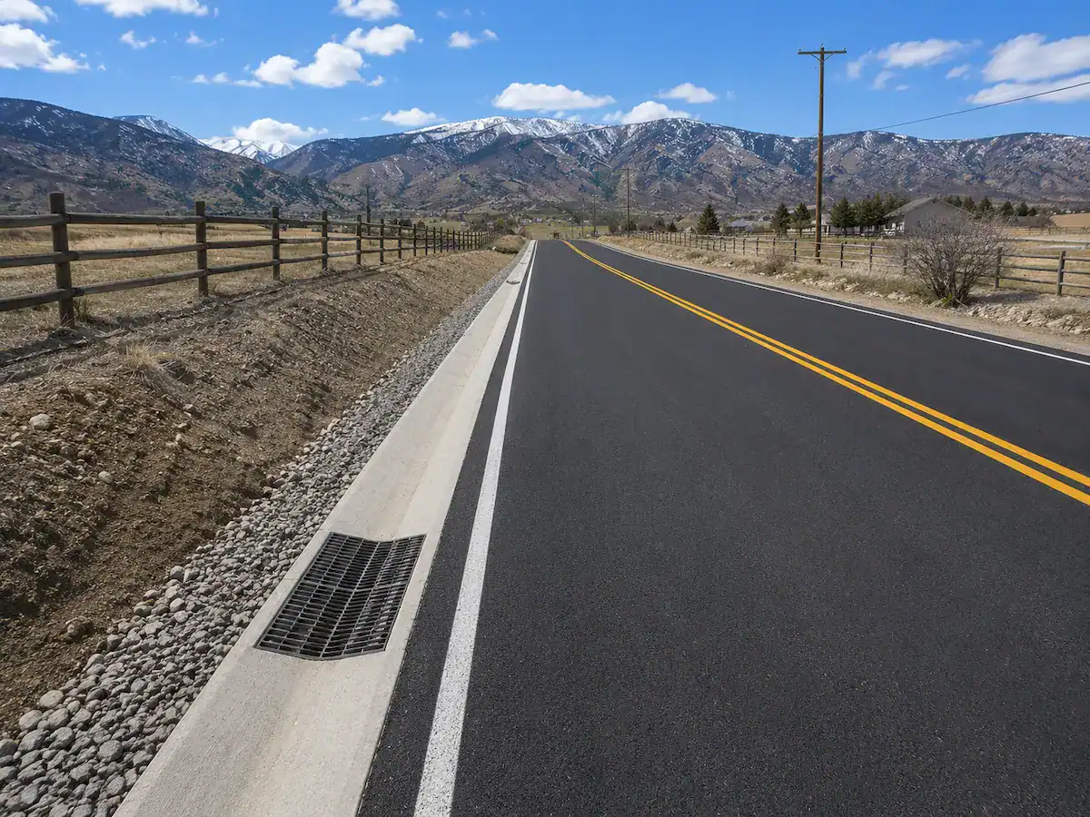Rural asphalt road in Utah featuring a roadside drainage system designed to manage stormwater runoff and protect pavement.