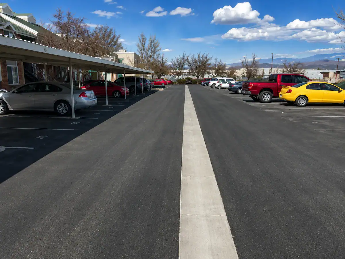 Residential parking lot in Utah featuring a concrete drainage channel integrated into fresh asphalt pavement.