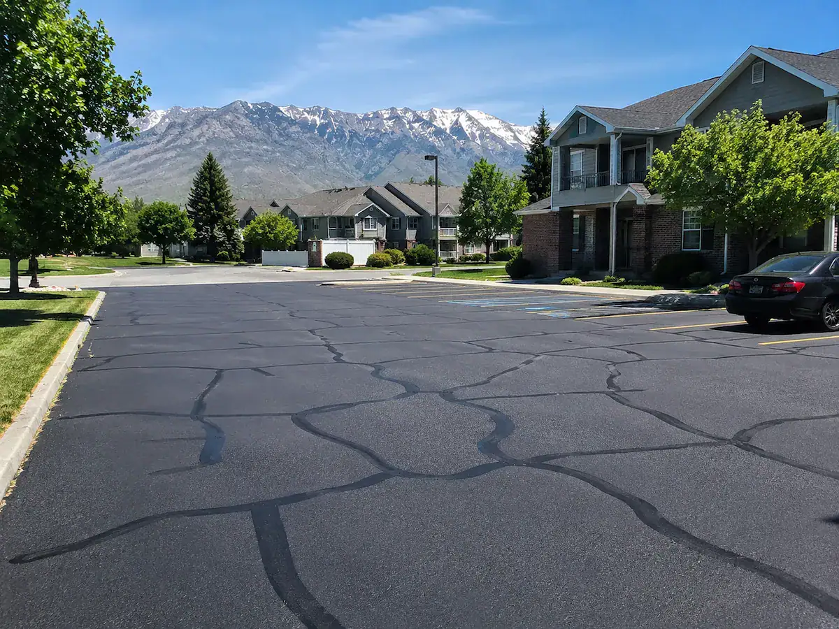 Residential parking lot in Utah with freshly sealed asphalt cracks and mountain views