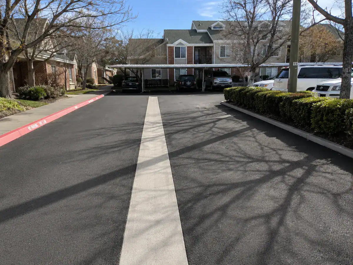 Residential community parking lot in Utah featuring a concrete drainage channel installed within fresh asphalt pavement.