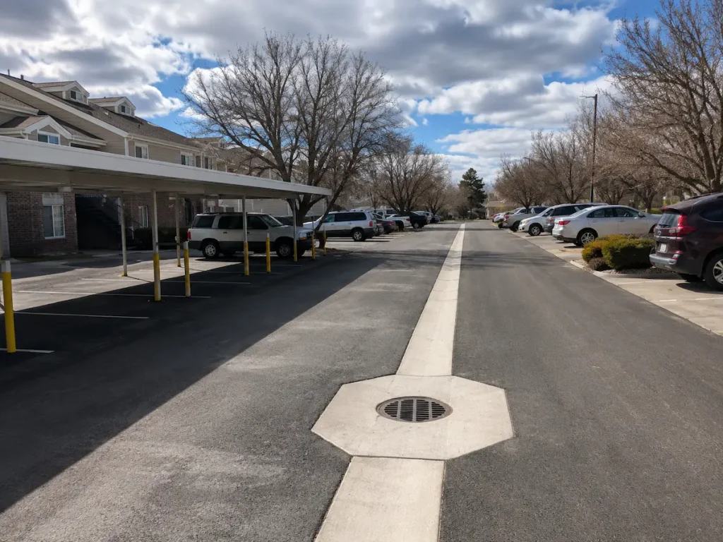 Residential parking area in Utah featuring a concrete storm drain system integrated into fresh asphalt pavement.