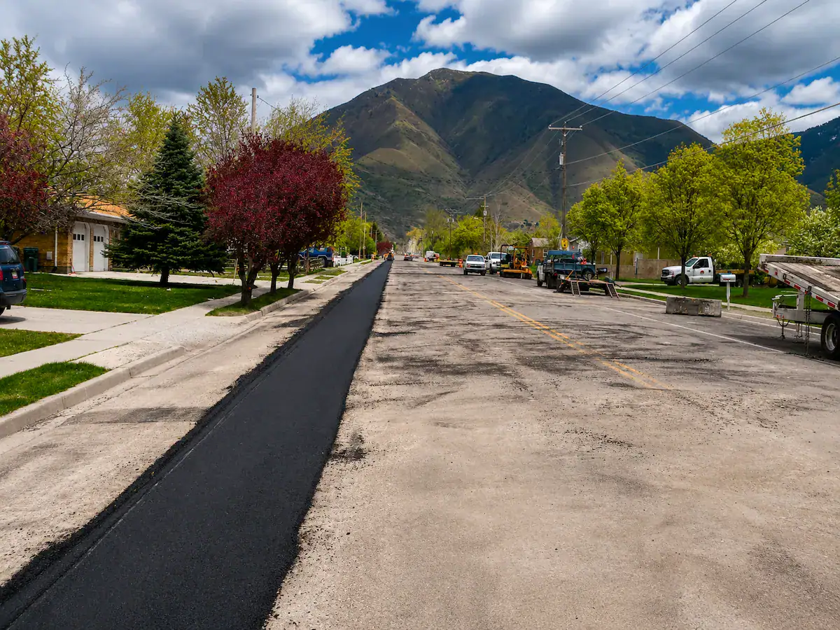 Long trench asphalt patching project on a Utah residential roadway with mountain views in the background.