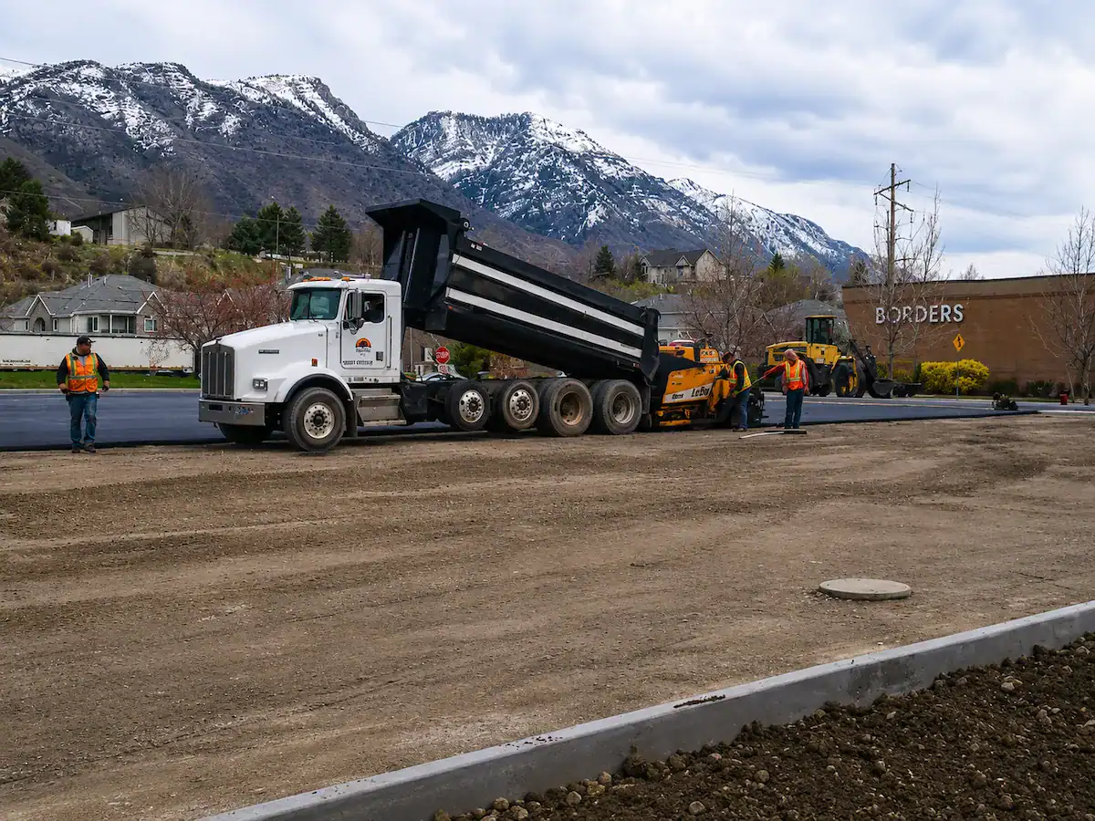Utah construction crew performing site preparation and asphalt paving with mountain views in the background.