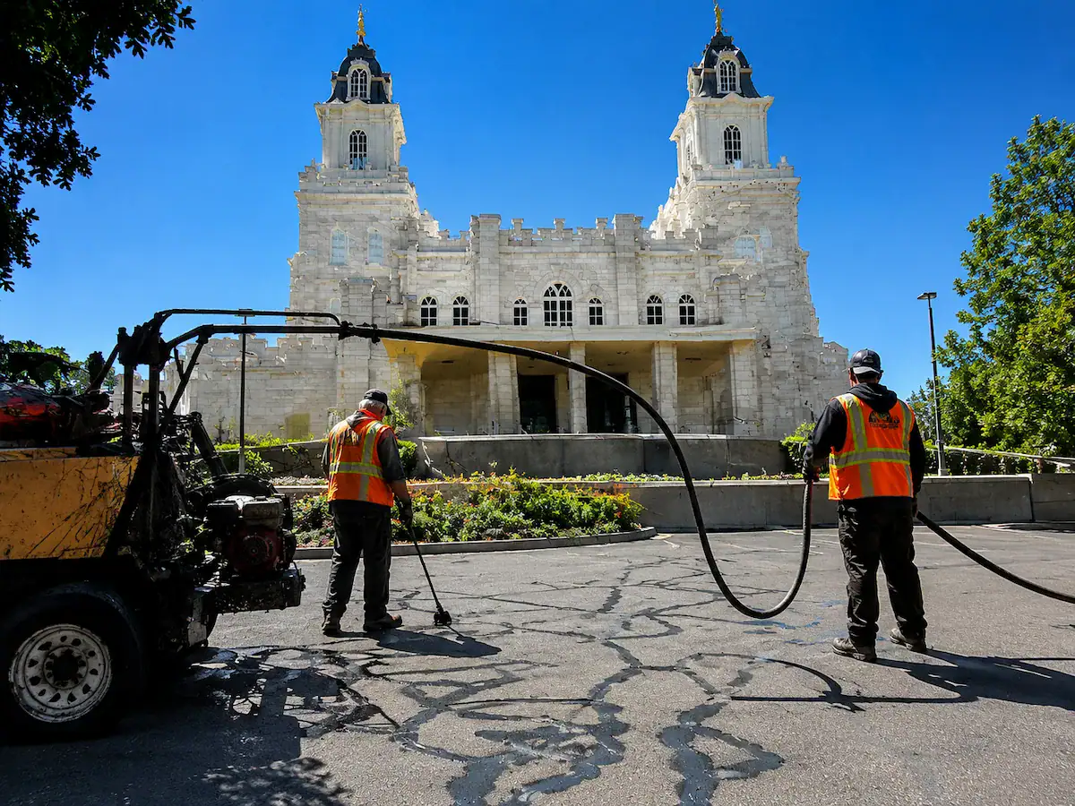 Asphalt crack sealing crew performing pavement maintenance near a Utah temple