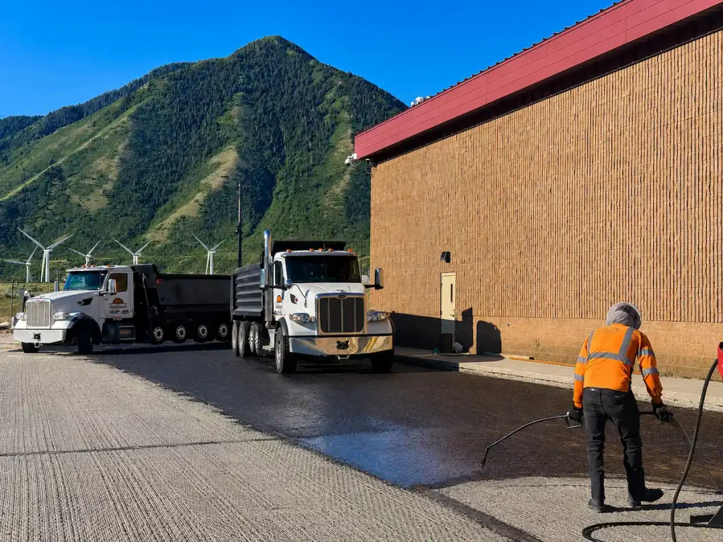 Asphalt paving crew applying tack coat during a commercial paving project in Ogden, Utah.