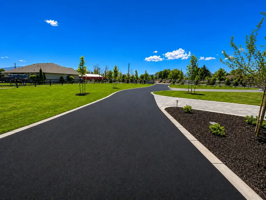 Freshly paved custom asphalt driveway at a residential property in Utah with concrete edging and landscaped surroundings.