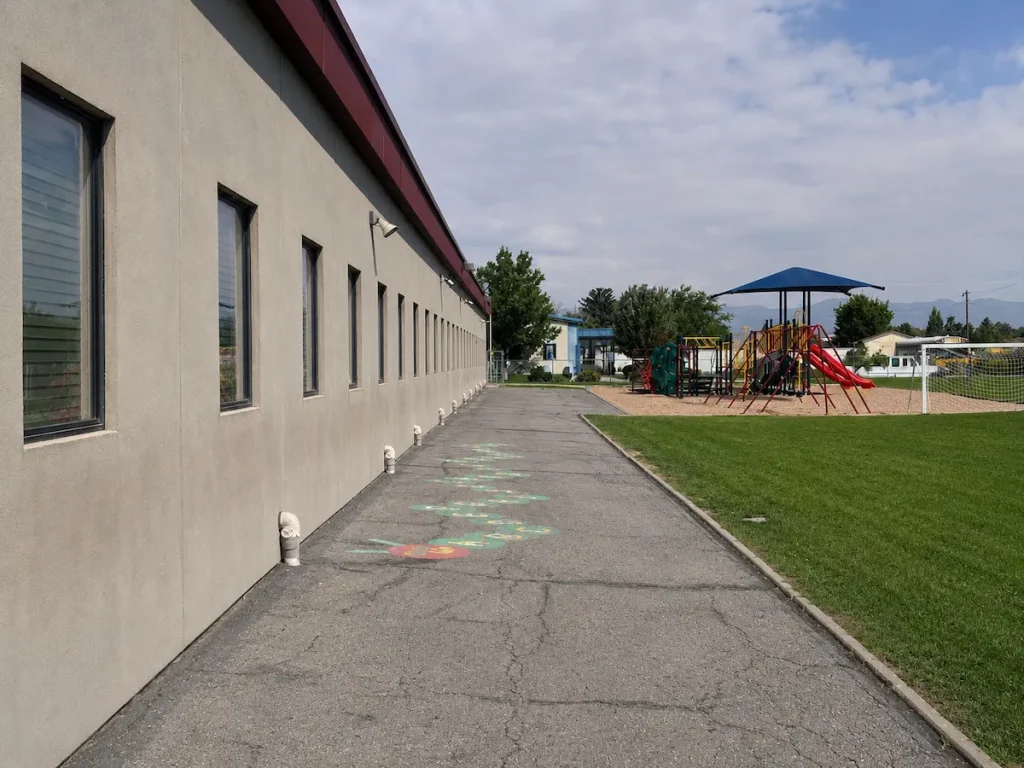 Before photo of weathered asphalt playground with faded play markings and surface cracks at Timpanogos Academy in Lindon, Utah before sealcoating.