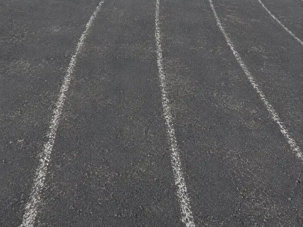 Before photo of faded running track lane striping on weathered asphalt at Timpanogos Academy in Lindon, Utah before restriping.