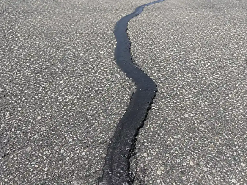 Close-up of fresh crack sealant applied to asphalt at the EOS Fitness parking lot in Orem, Utah.