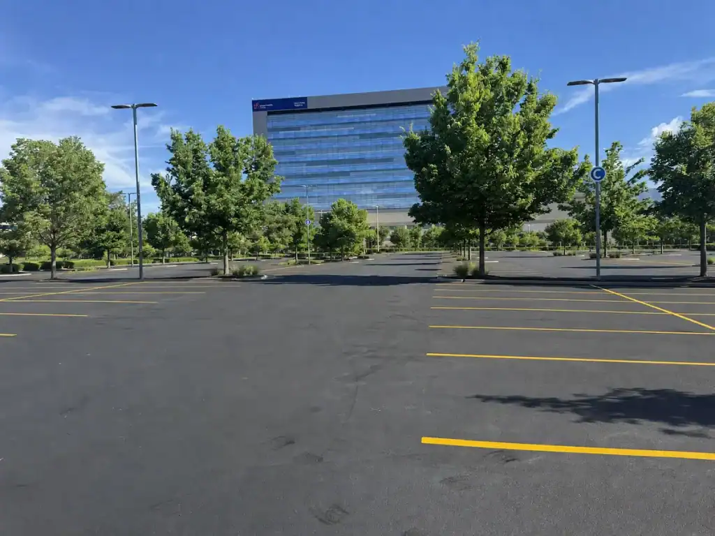 Empty parking lot with faded asphalt and yellow parking lines in front of Utah Valley Hospital in Provo, Utah.