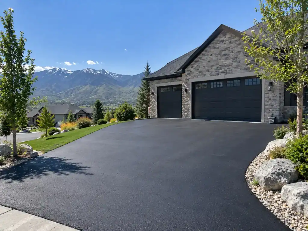 Freshly paved asphalt driveway at a Utah home with mountains in the background.