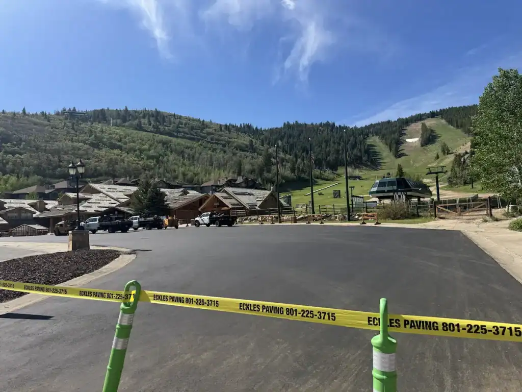 Completed asphalt paving at Deer Valley Resort in Park City, Utah, with ski slopes and resort buildings in the background.