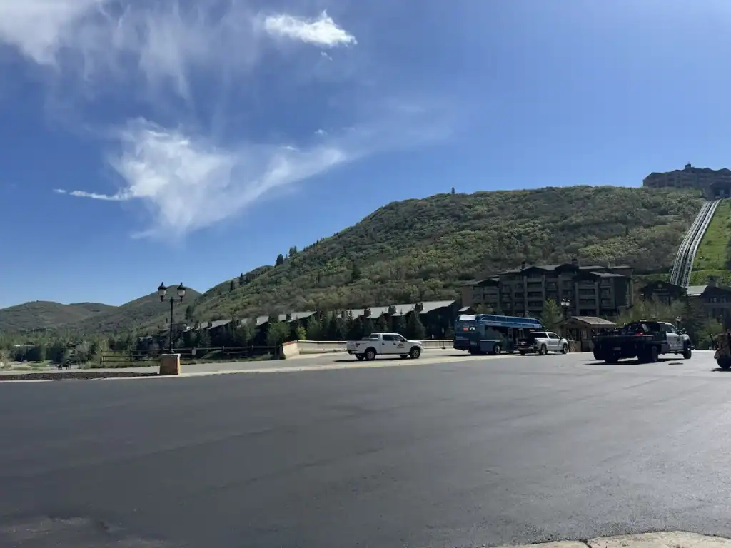 Newly paved asphalt surface at Deer Valley Resort in Park City, Utah, with resort buildings and mountain slopes in the background.