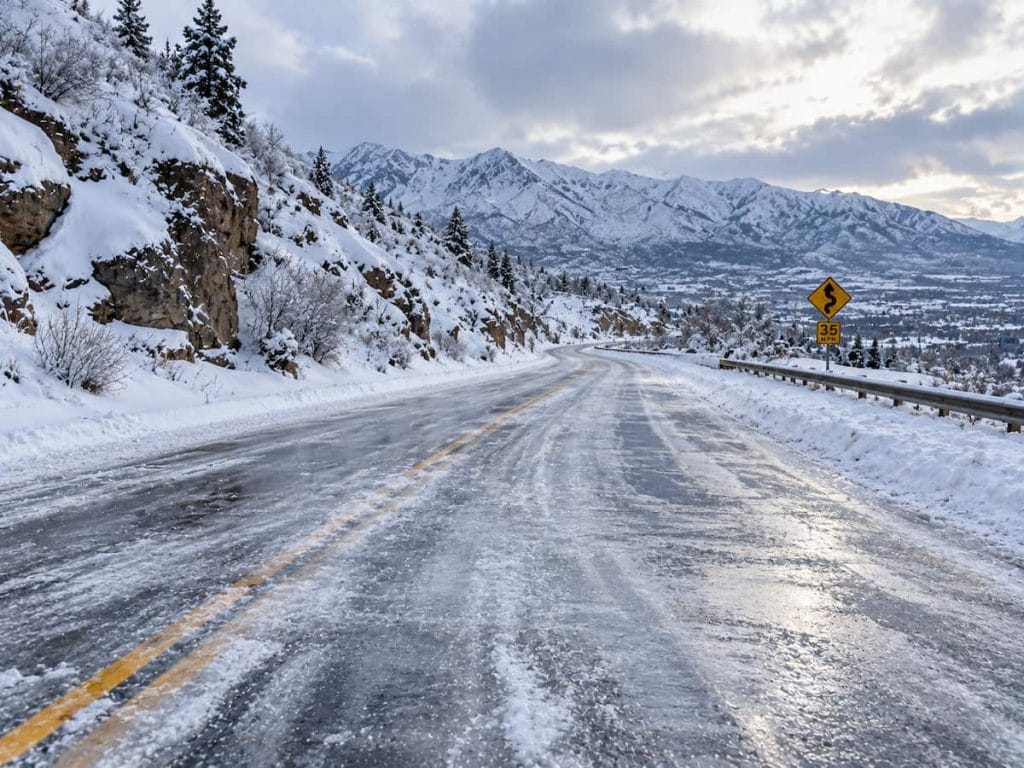 Utah asphalt road covered with ice and snow during winter weather in the mountains.