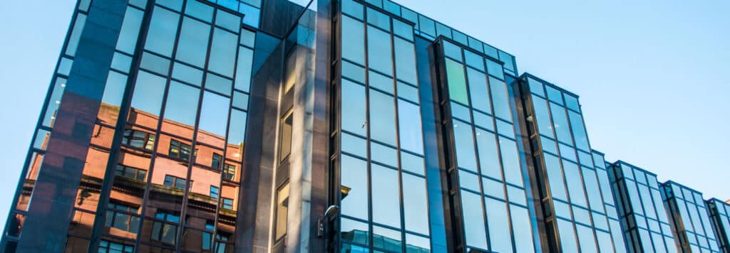 Modern glass office building reflecting surrounding architecture, showcasing innovative workspace design.