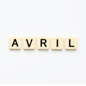 Mot « avril » formé avec des lettres de type Scrabble beiges sur fond blanc minimaliste, représentant le mois de mai pour un article voyage « Où aller en Europe en avril ».