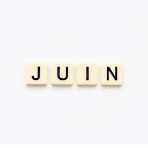 Mot « juin » formé avec des lettres de type Scrabble beiges sur fond blanc minimaliste, représentant le mois de mai pour un article voyage « Où aller en Europe en juin ».