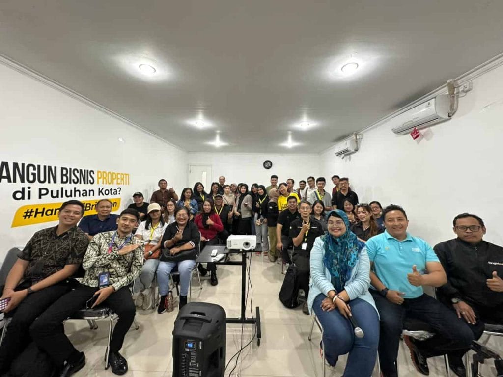 Kelompok orang mengikuti seminar tentang bisnis properti di ruangan yang modern.