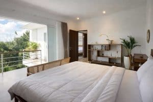 Kamar tidur villa tropis modern di Nusa Dua dengan balkon menghadap pemandangan GWK dan sunset yang.