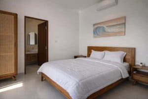 Kamar tidur minimalis dengan tempat tidur nyaman dan dekorasi alami di villa tropis Nusa Dua.