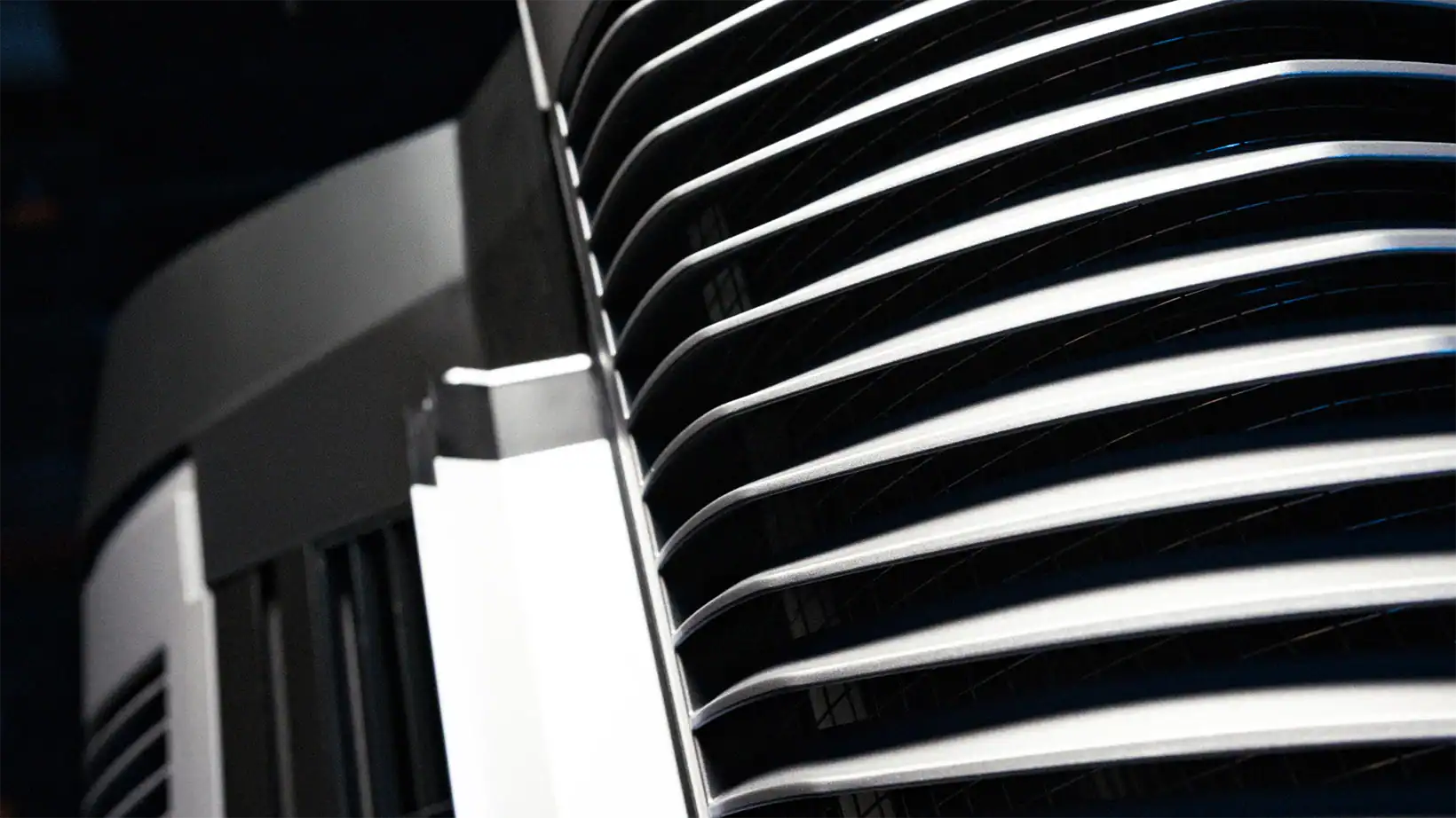 Close-up detail of the Vector evaporative cooler’s vent fins, emphasizing the precision-engineered grille design and smooth metallic finish under directional lighting