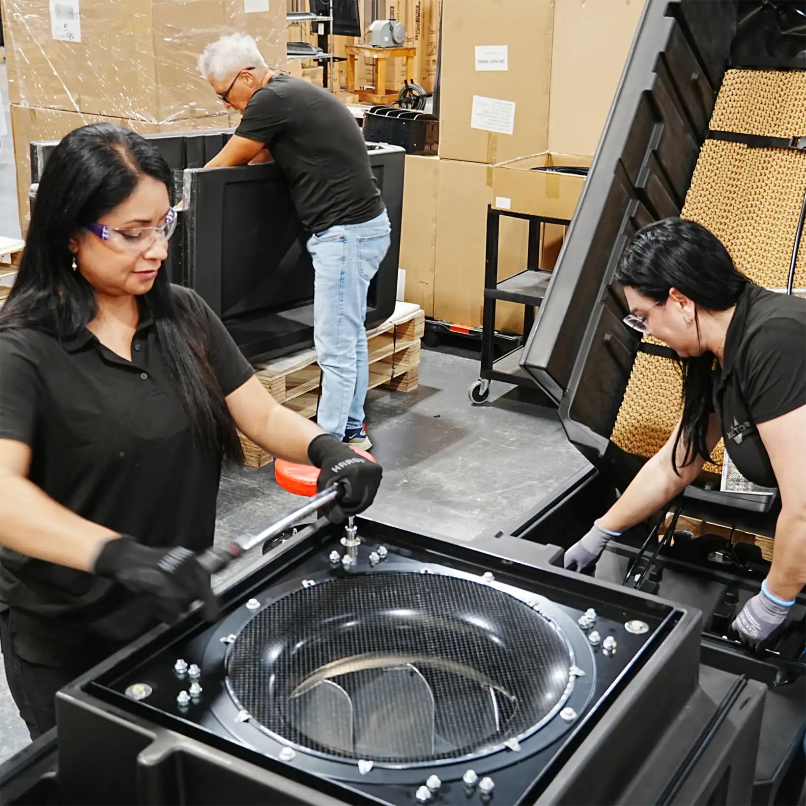 Assembly team working on Spartan evaporative coolers in a manufacturing facility, securing components and installing filtration units.