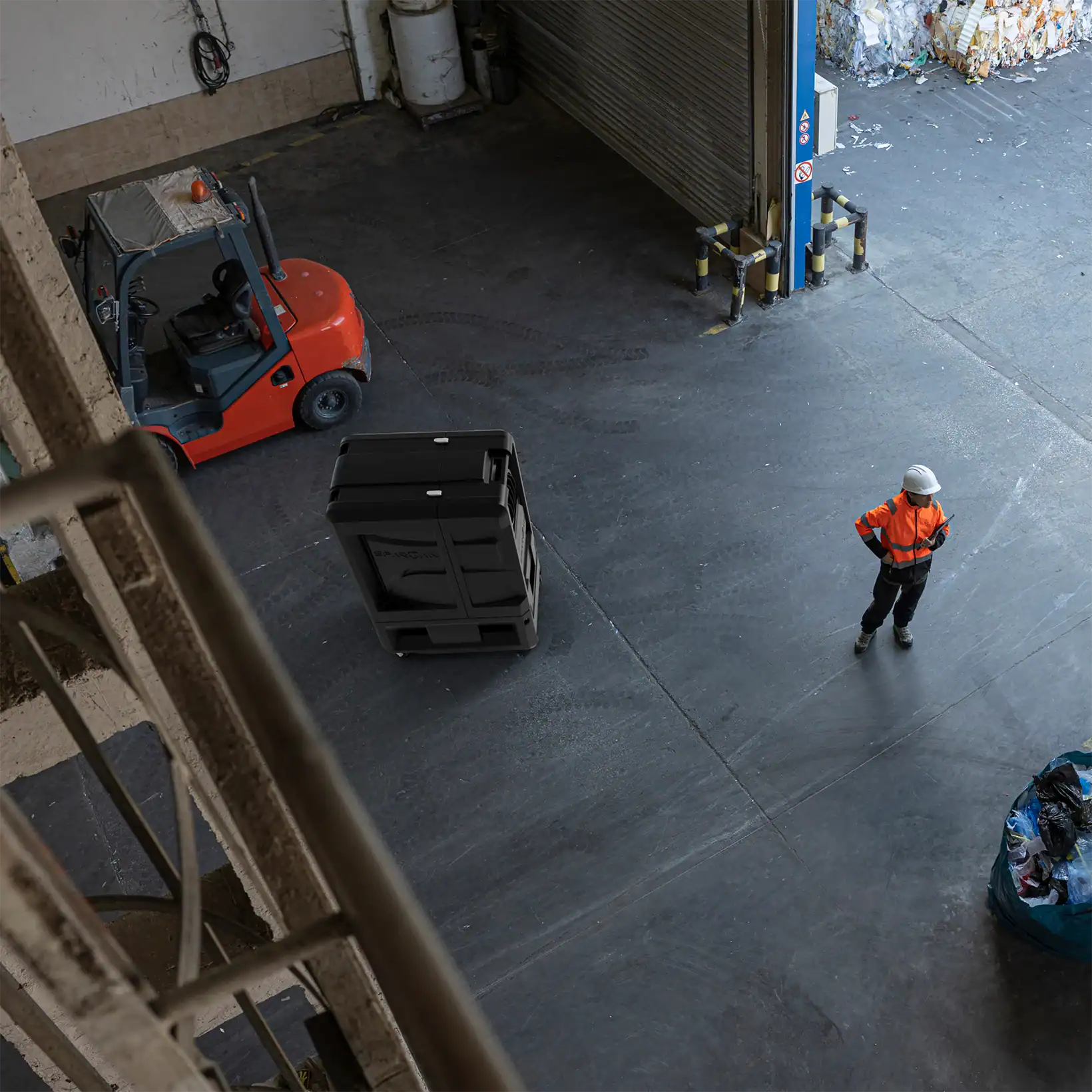 Overhead view of a Spartan evaporative cooler in an industrial warehouse, with a worker in safety gear and a forklift nearby.