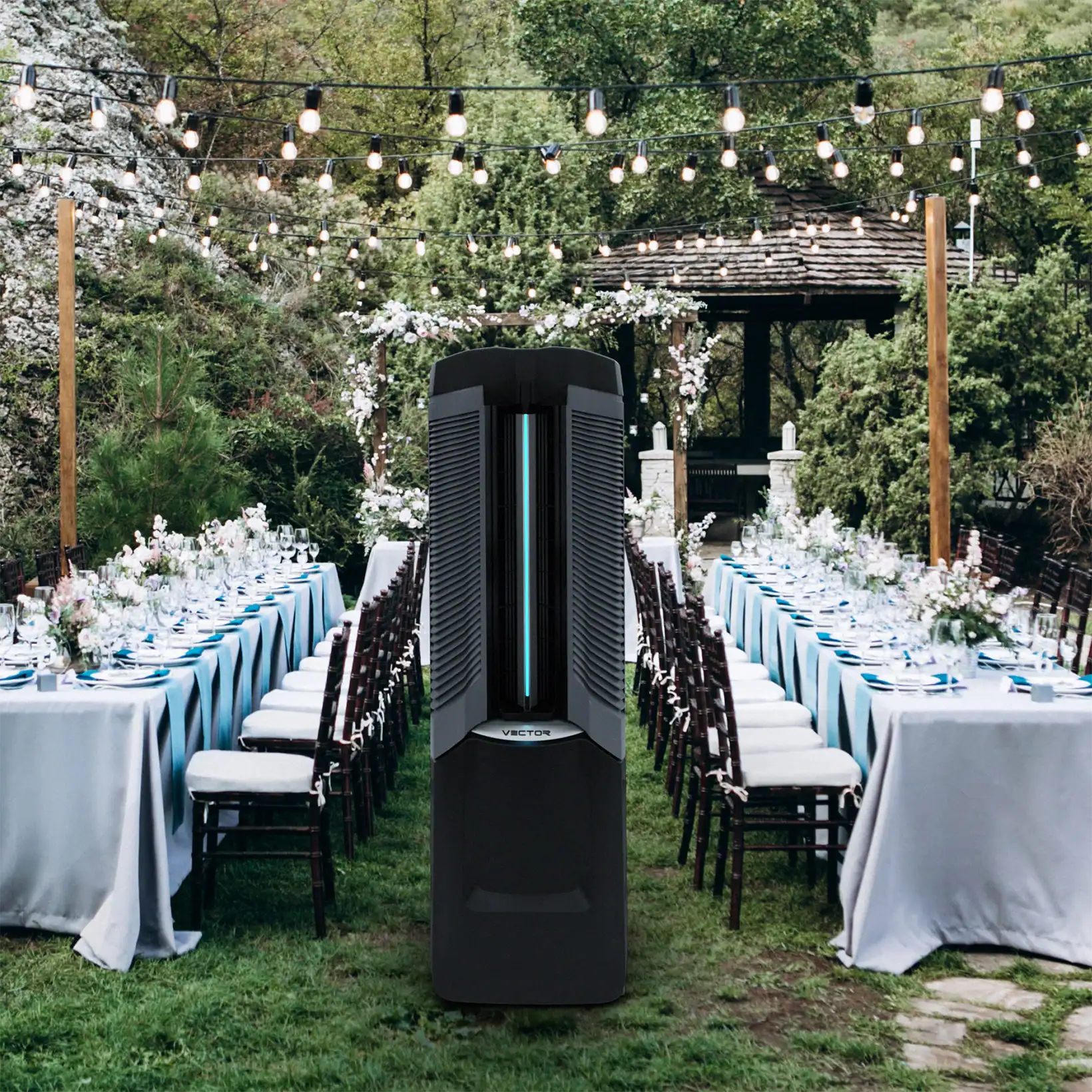 The Vector evaporative cooler positioned between elegant outdoor dining tables at a garden event, providing sleek, powerful cooling with a modern design that complements the setting.