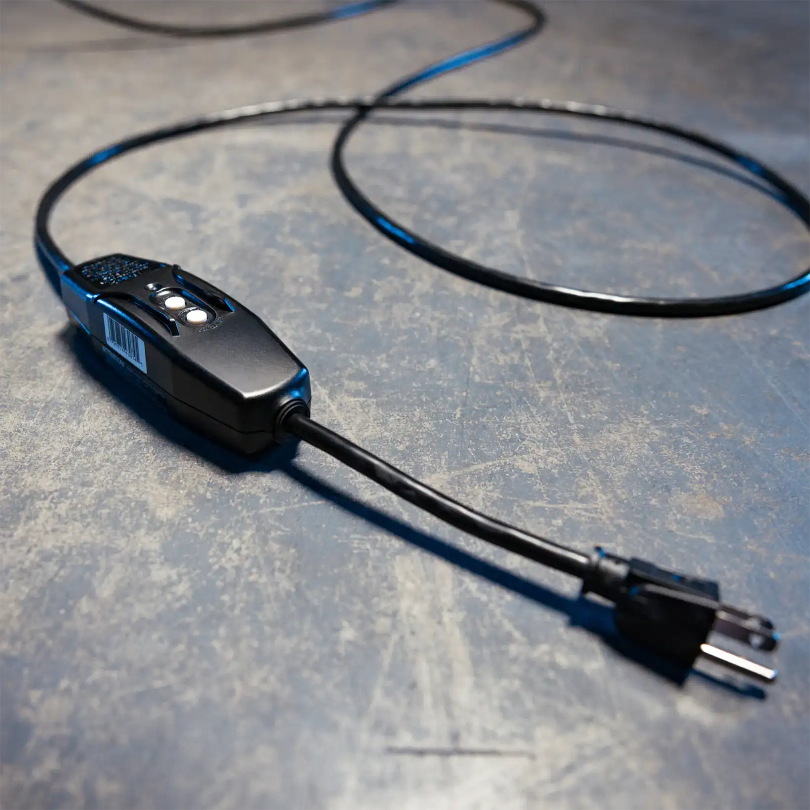 Close-up of an evaporative cooler’s power cord and control plug on an industrial floor.