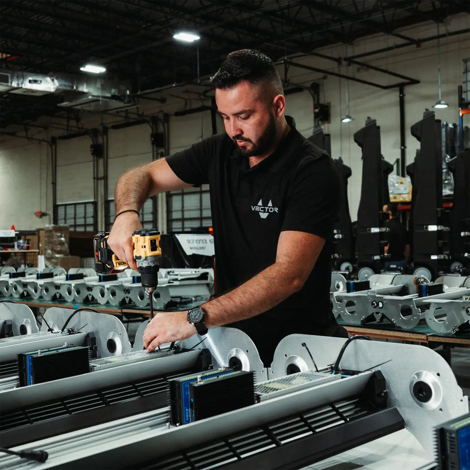 Technician assembling Vector evaporative coolers in a production facility, using a power drill during manufacturing.