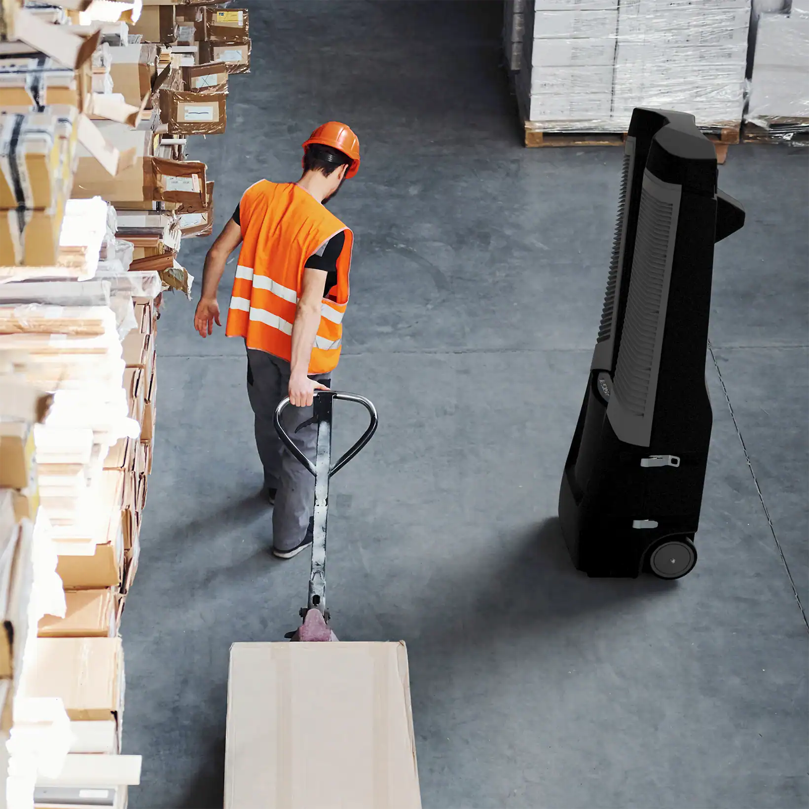 Warehouse worker in safety gear operating a pallet jack beside the Vector evaporative cooler.