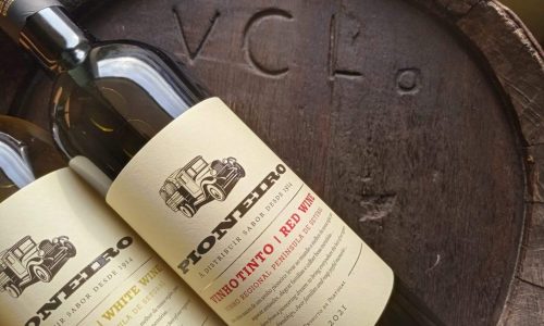 Vinho tinto da Região Península de Setúbal, na garrafa com rótulo clássico e moderna, sobre um laga de madeira antigo, refletindo tradição e qualidade do vinho português Venâncio da Costa Lima.