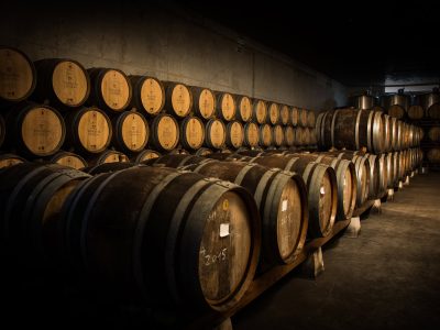 Barricas de vinho envelhecido na adega da Vinícola Venâncio da Costa Lima, destacando tradição e qualidade na produção de vinhos portugueses.