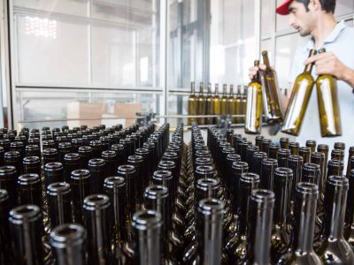 Registos de garrafas de vinho em linha na adega, preparação para engarrafamento na vinícola de Venâncio da Costa Lima. Ambiente de produção de vinhos de alta qualidade e tradição no Algarve, Portugal.