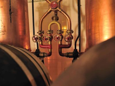 Cabeçalho alternativo: Sistema de aquecimento e tubagens de cobre na cave de vinificação da Vinícola Venâncio da Costa Lima, destacando a tradição e tecnologia na produção de vinho em Portugal.