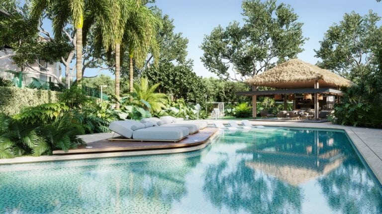 Luxurious tropical pool area at Vida Pinilla resort with loungers and thatched cabana, surrounded by lush greenery.