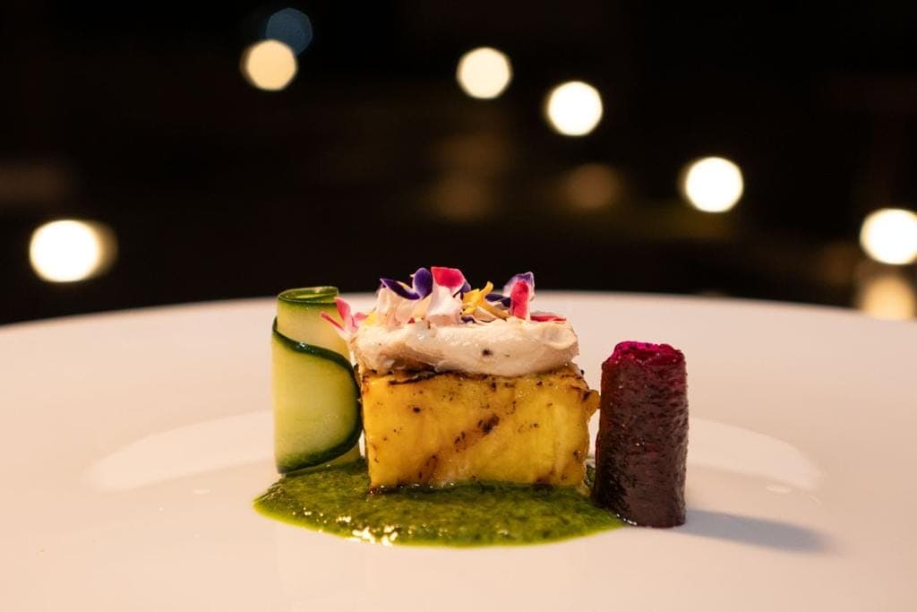 Delicious plated dish featuring grilled pineapple, cucumber roll, and beetroot on a white plate.