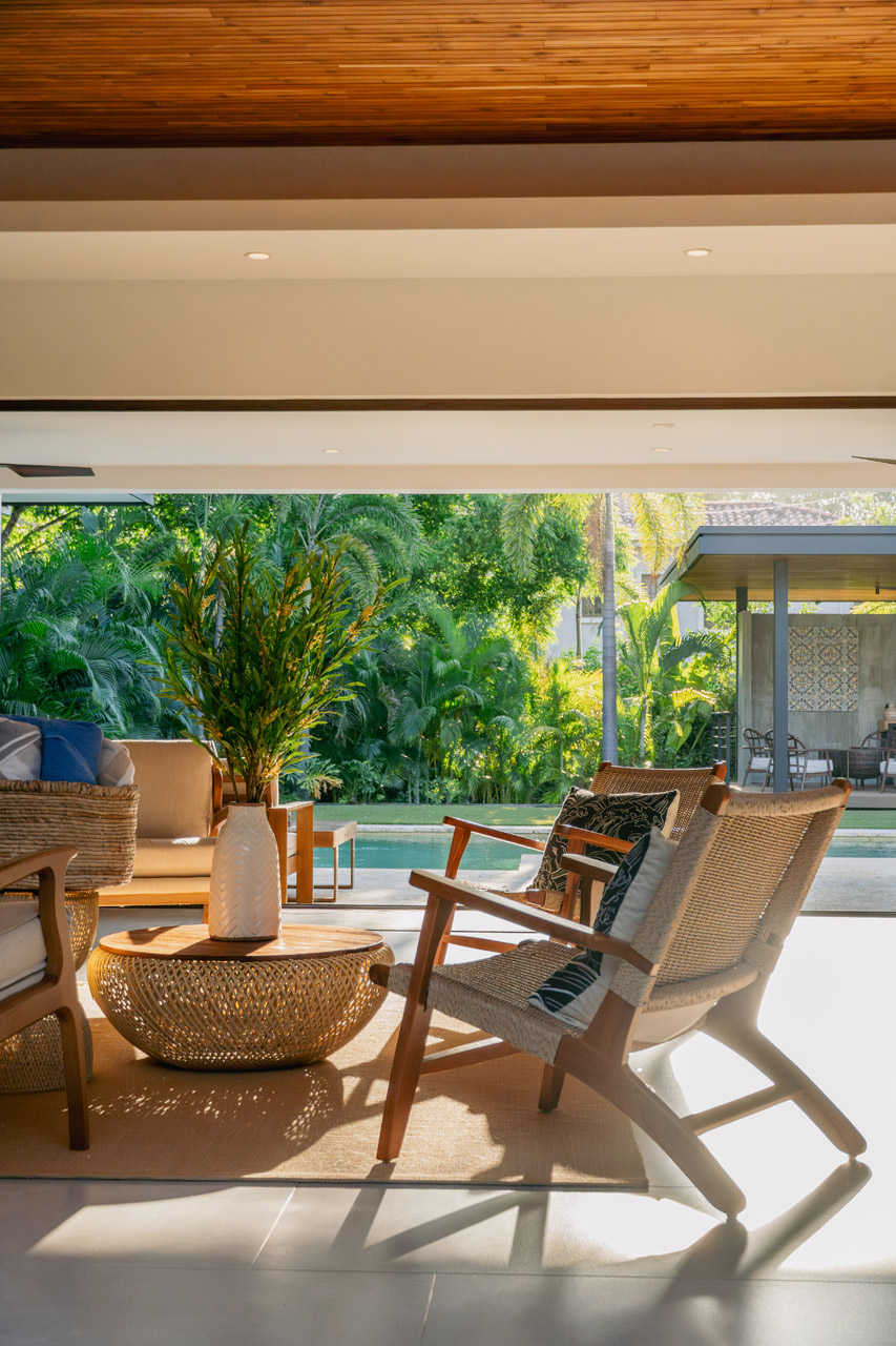 Stylish indoor outdoor living space with tropical garden views and modern furniture.