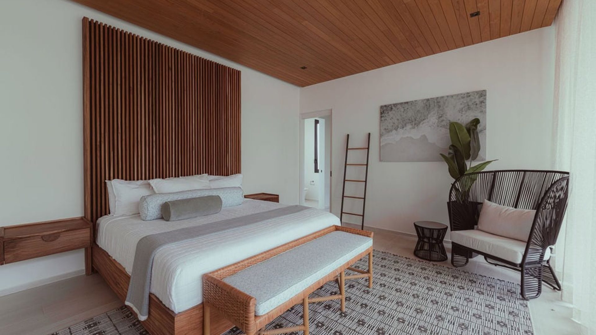 Modern bedroom with wooden accents and cozy seating for relaxation.