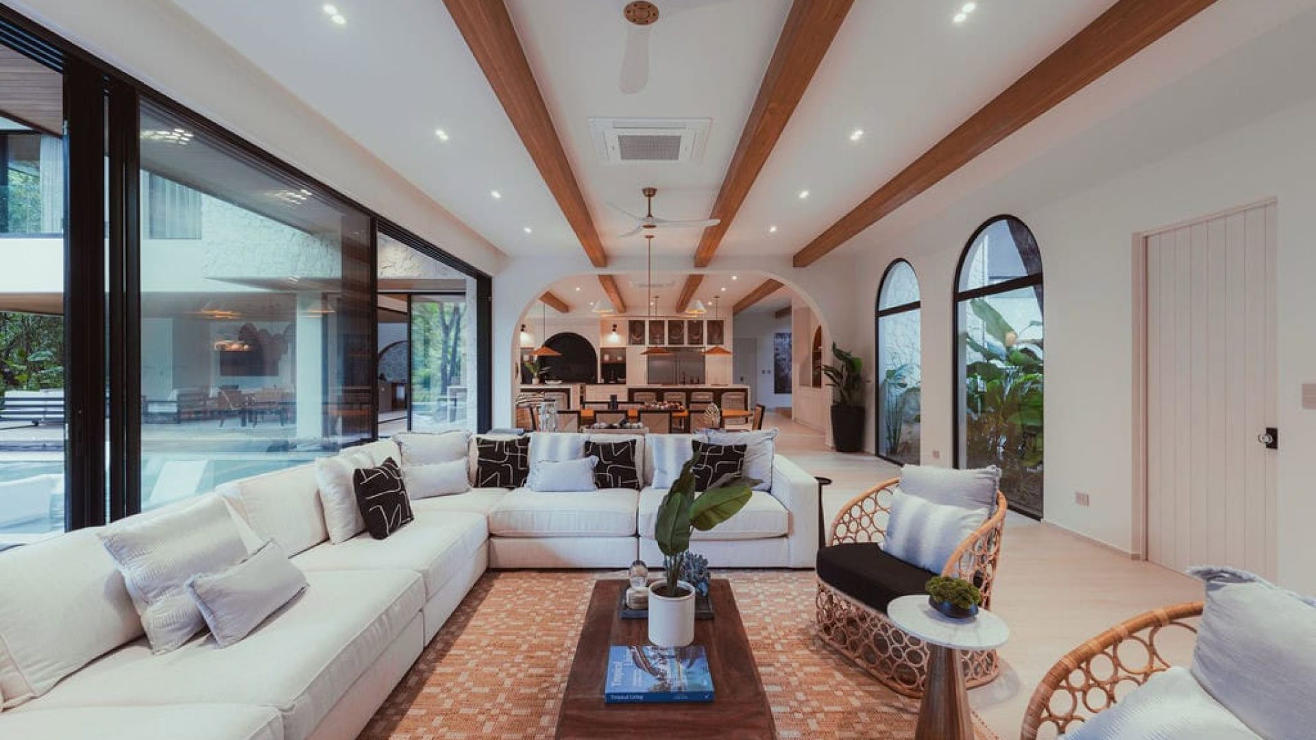 Bright living room with modern design and large glass windows overlooking outdoor pool area.